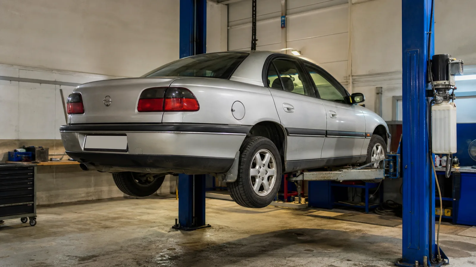 Opel Omega на подъёмнике при осмотре заднего привода — иллюстрация